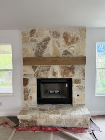 Natural stone fireplace with a stone hearth and wood mantel