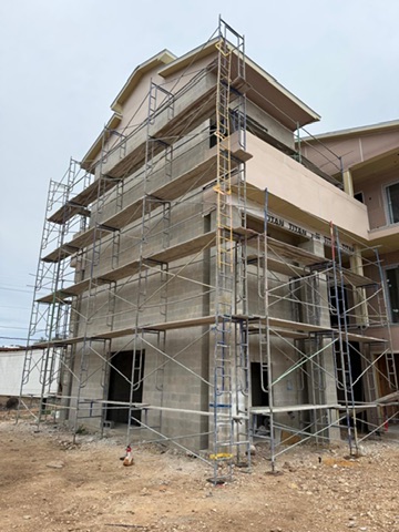 Stucco application underway on a multi-story exterior behind scaffolding